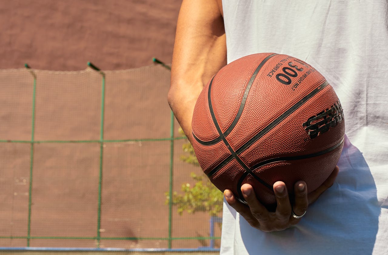services-03 Hand holding a basketball on an outdoor court, ready for play.
