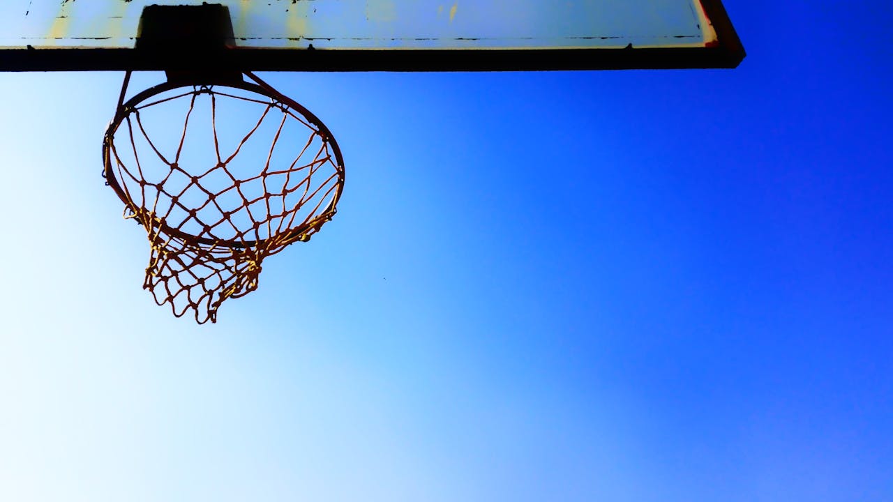 journey A basketball hoop silhouetted against a vibrant clear blue sky, perfect for sports themes.